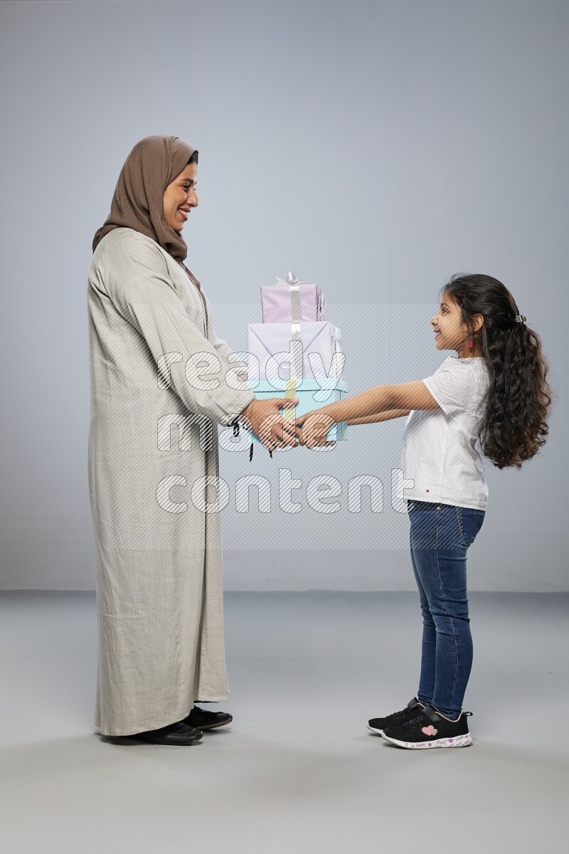 A girl giving a gift to her mother on gray background