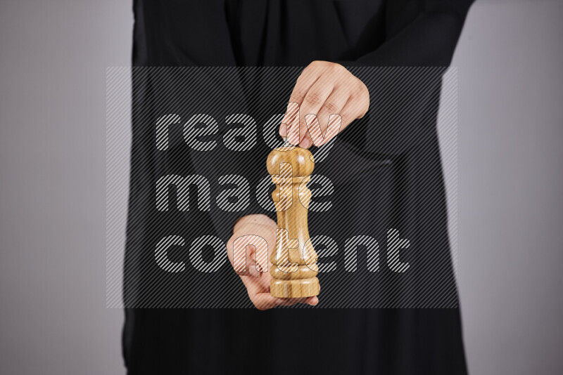 A woman in black abaya holding different wooden essentials in different positions