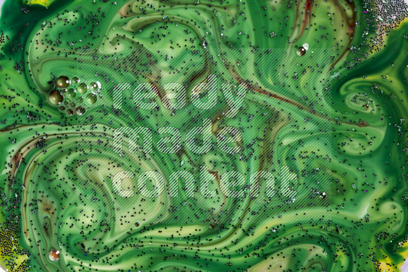 A close-up of sparkling green glitter scattered on swirling green and red background
