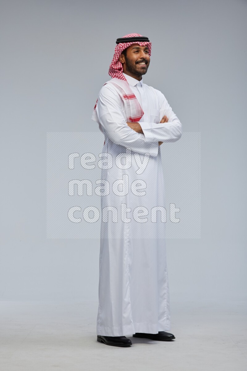 Saudi man Wearing Thob and shomag standing with crossed arms on Gray background