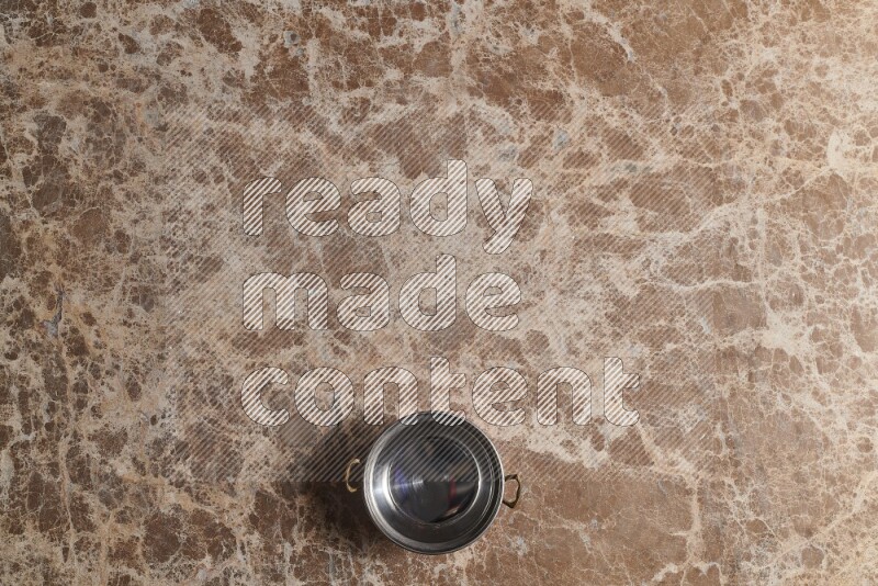 A small copper pot on beige marble background
