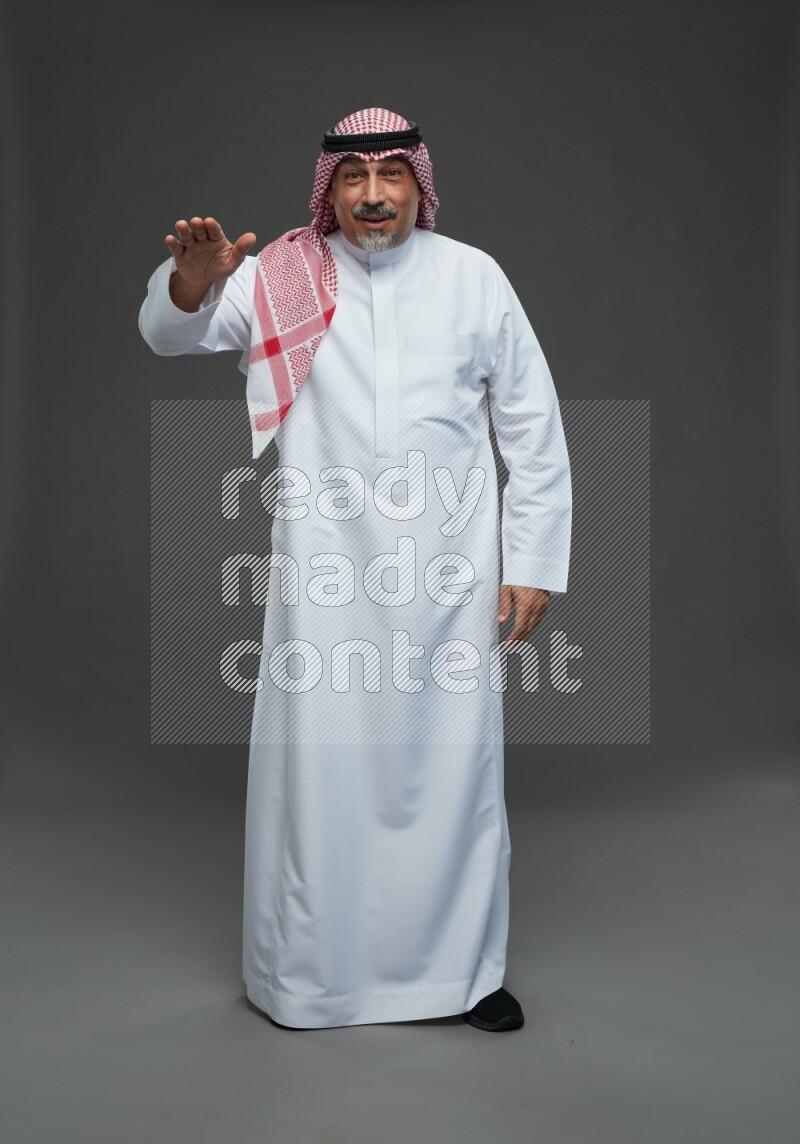 Saudi man with shomag Standing Interacting with the camera on gray background