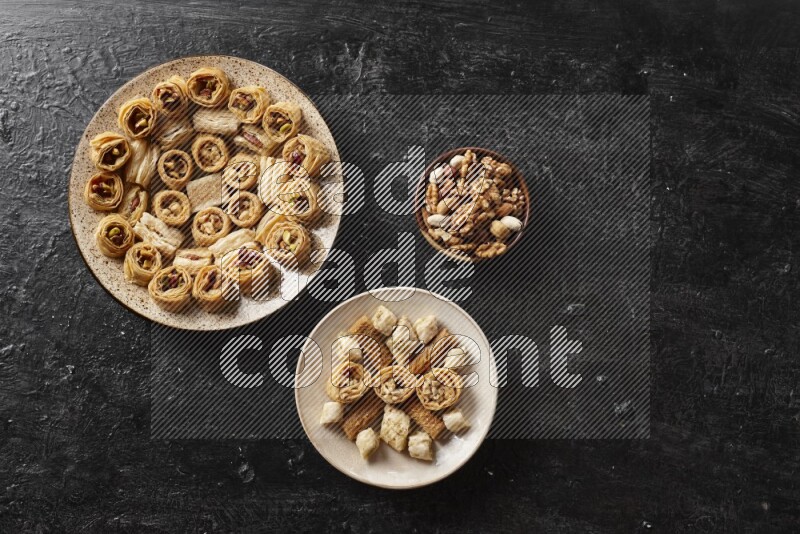 Oriental sweets in pottery plates with nuts in a dark setup