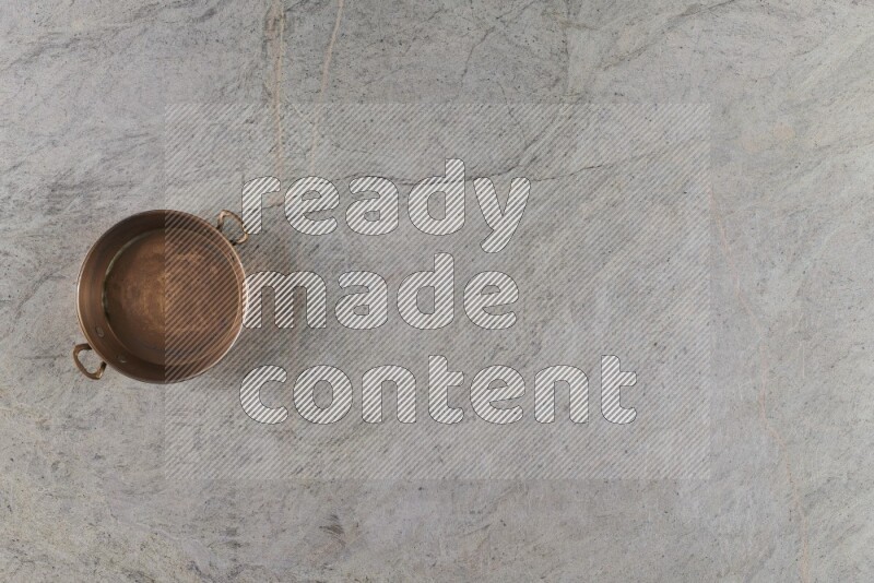 A small copper pan on grey marble background