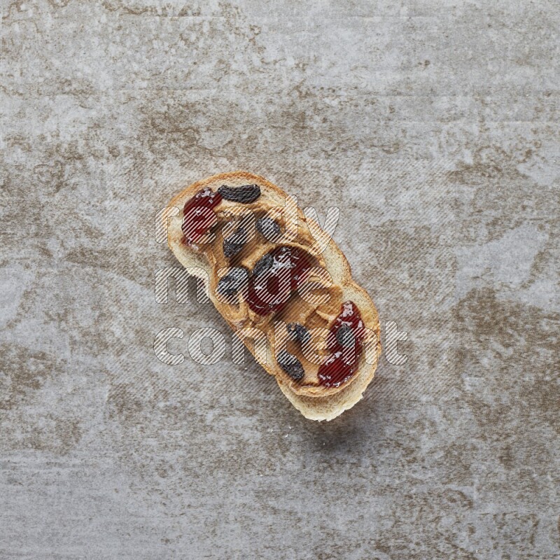 open faced peanut butter sandwich with jam and dried cranberries on a grey textured background