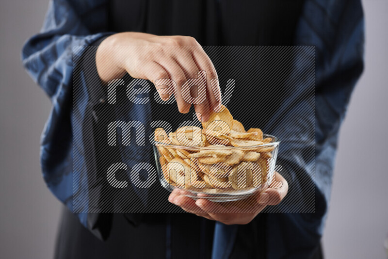 Woman in abaya holding different kinds of snacks in different positions
