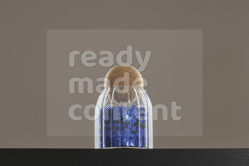 Sequins in a glass jar on black background
