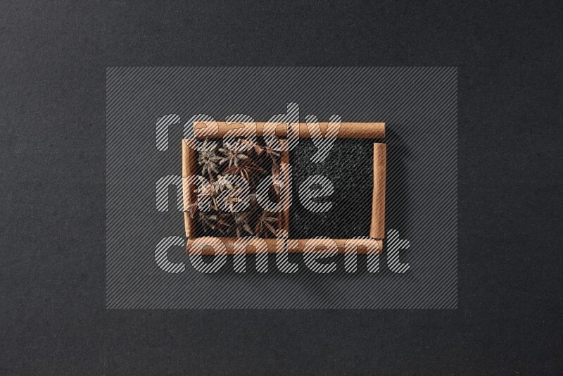 2 squares of cinnamon sticks full of black seeds and star anise on black flooring