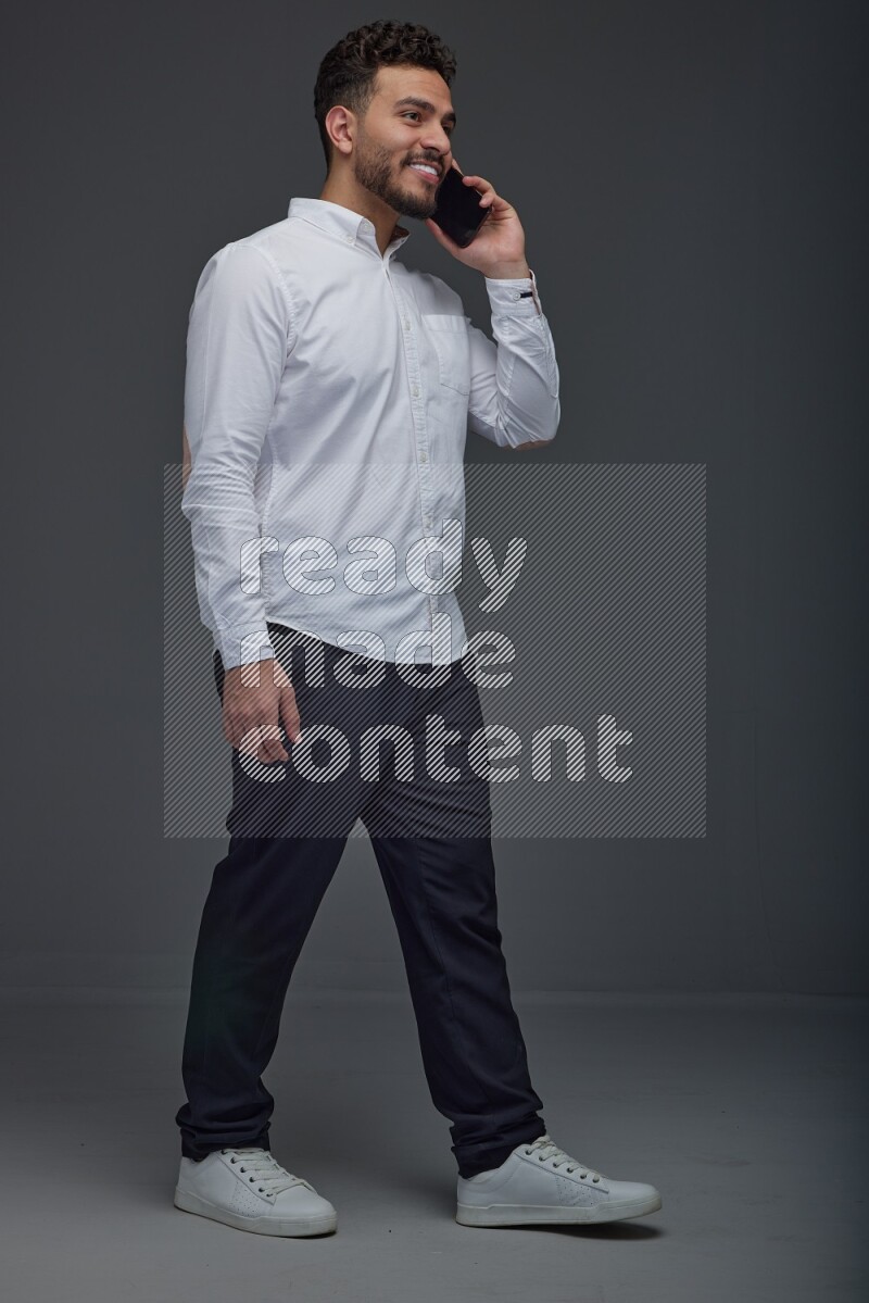 A man wearing smart casual talking in the phone eye level on a gray background