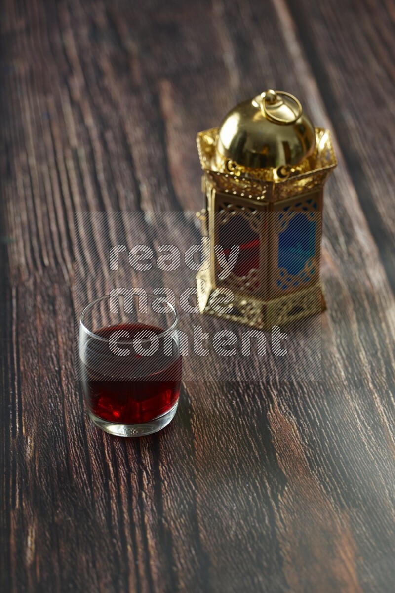 A golden lantern with different drinks, dates, nuts, prayer beads and quran on brown wooden background