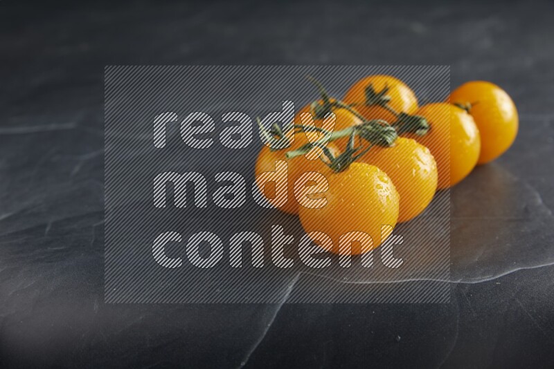Yellow cherry tomato vein on a textured black slate background 45 degree