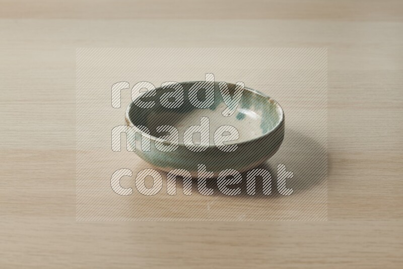 A multicolored pottery bowl on light wooden background