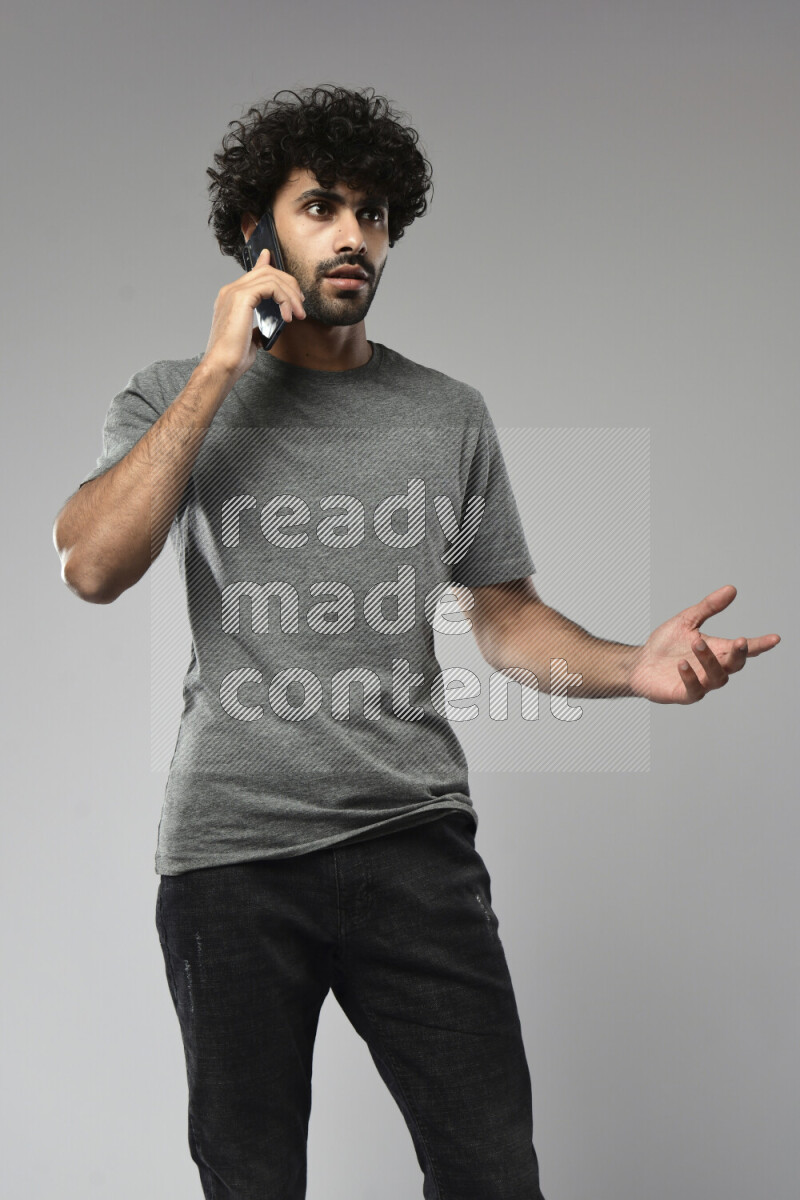 A man wearing casual standing and talking on the phone on white background