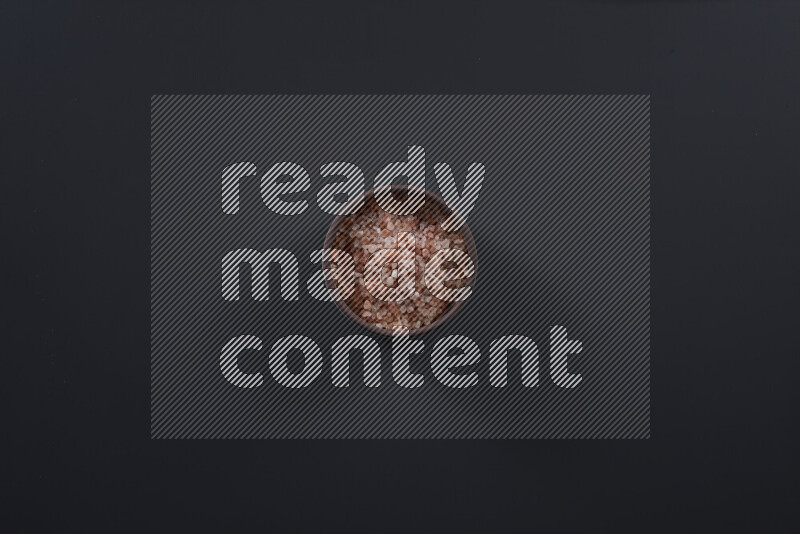 Pottery bowl full of fine himalayan salt and coarse himalayan salt on black background