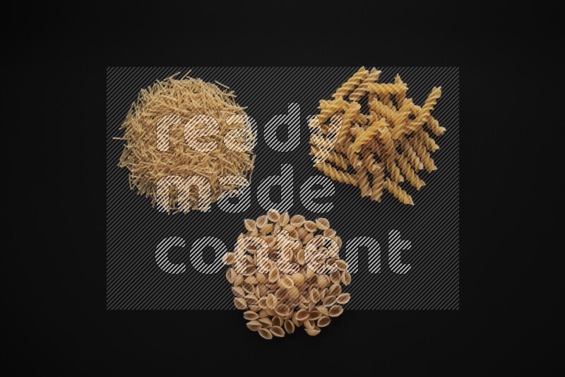 Different pasta types in bunches on black background