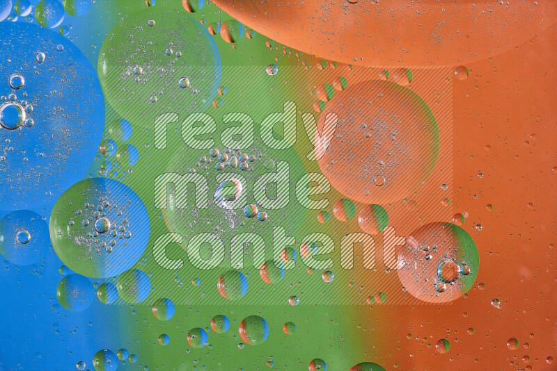 Close-ups of abstract oil bubbles on water surface in shades of orange, green and blue