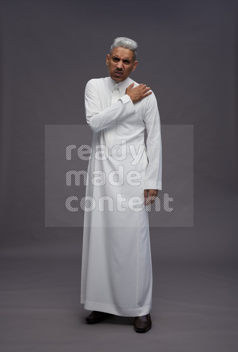 Saudi man wearing thob standing interacting with the camera on gray background