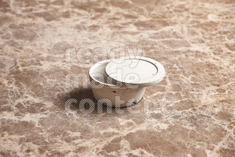 A white pottery bowl on beige marble background