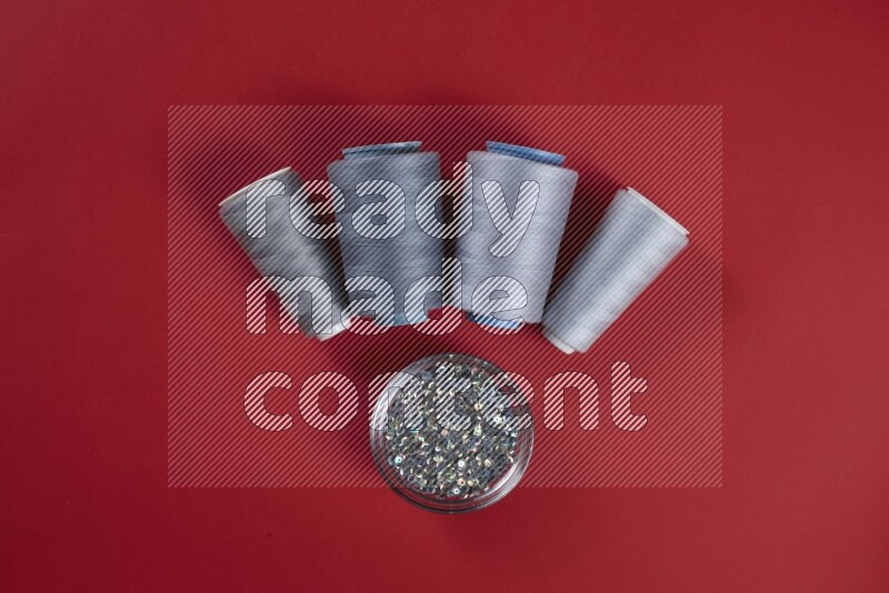 A grey collection of sewing and tailoring tools arranged on a red background