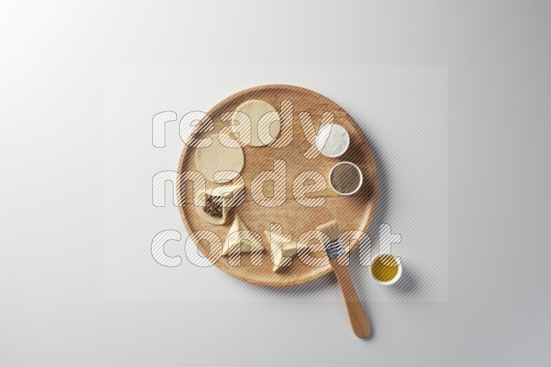 two closed sambosas and one open sambosa filled with meat while salt, black pepper and oil with oil brush aside in a wooden dish on a white background