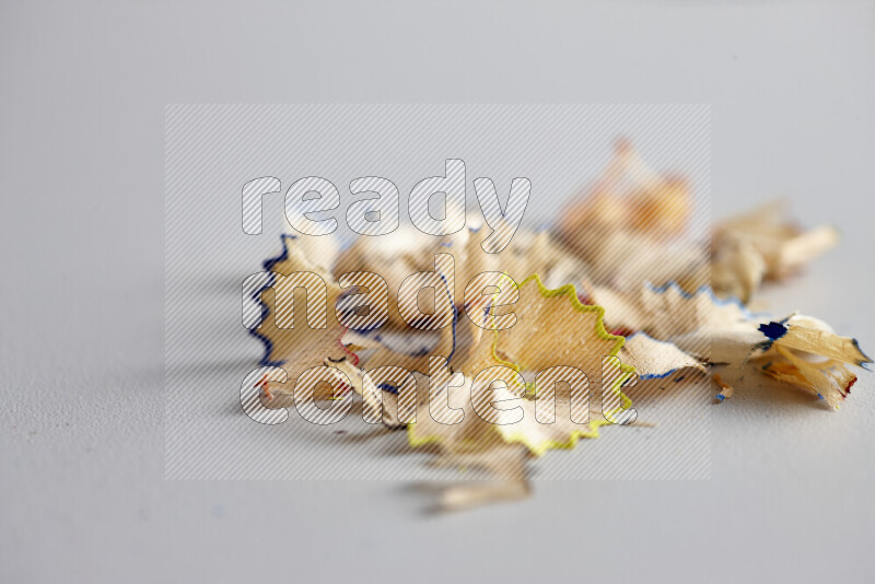 A close-up showing a small pile of pencil shavings with varied color edges on grey background