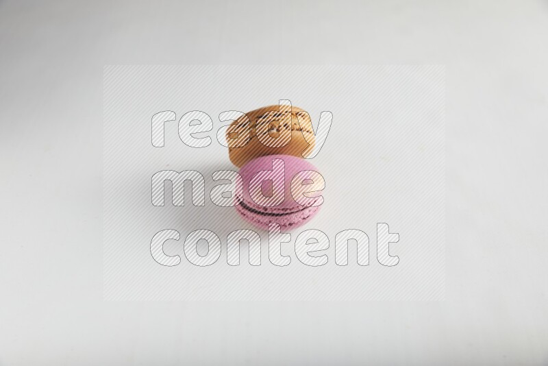 45º Shot of of two assorted Brown Irish Cream, and Purple Strawberry macarons on white background