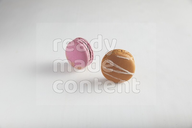 45º Shot of of two assorted Brown Irish Cream, and Purple Strawberry macarons on white background