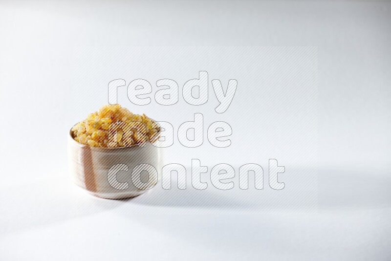 A beige ceramic bowl full of raisins on a white background in different angles