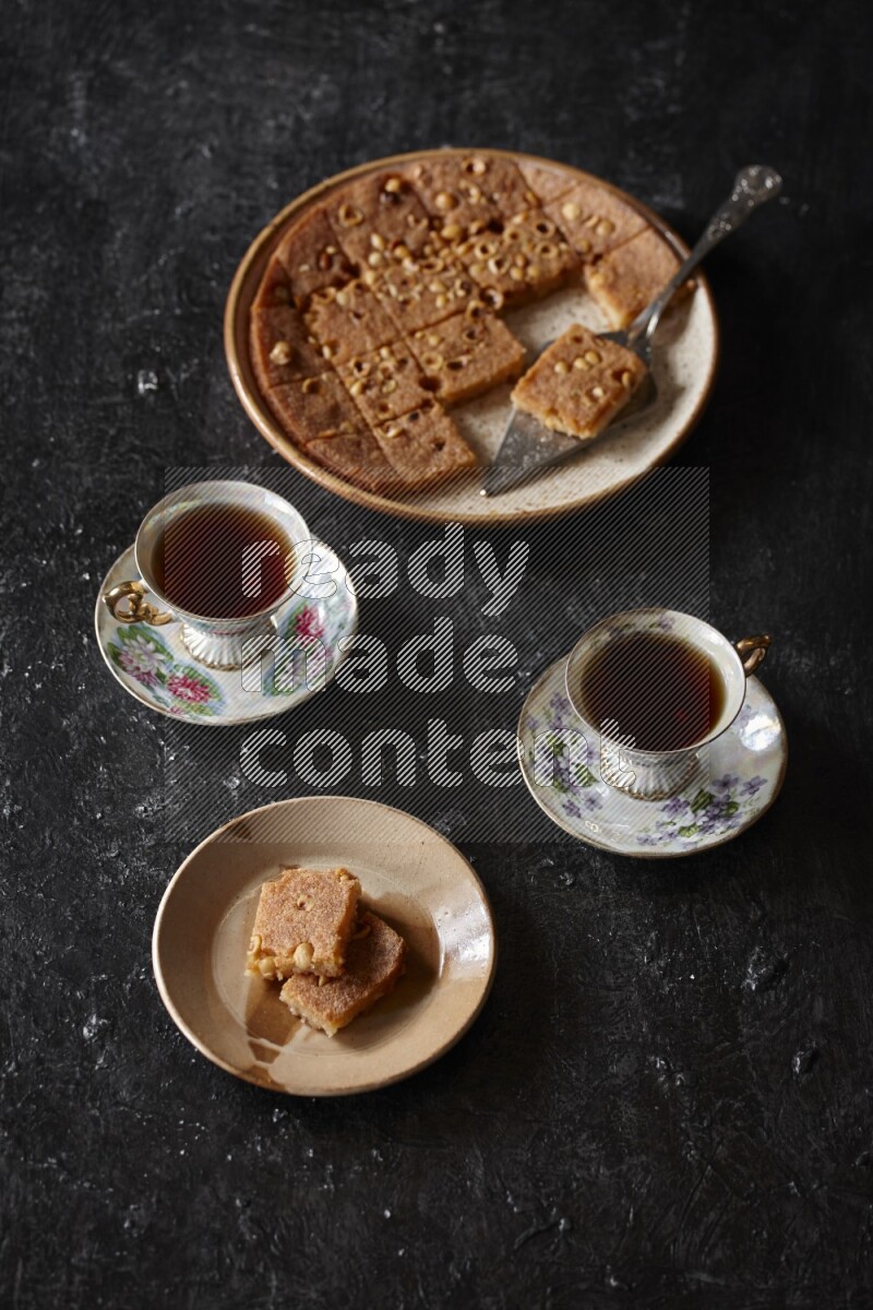 Basbousa with tea in a dark setup