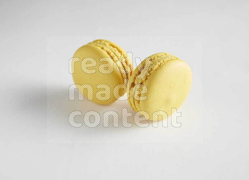 45º Shot of two Yellow Lemon macarons on white background