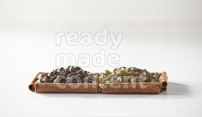 2 squares of cinnamon sticks full of cardamom and coffee beans on white flooring