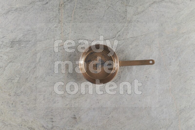 A small copper pan on grey marble background
