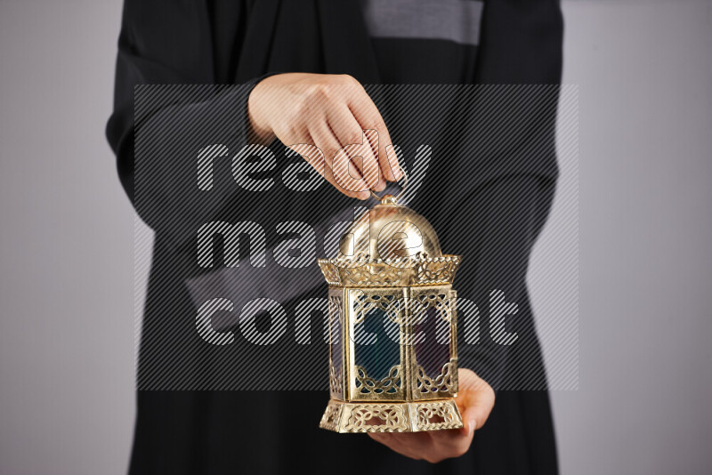A woman in black abaya holding different ramadan lanterns in different positions