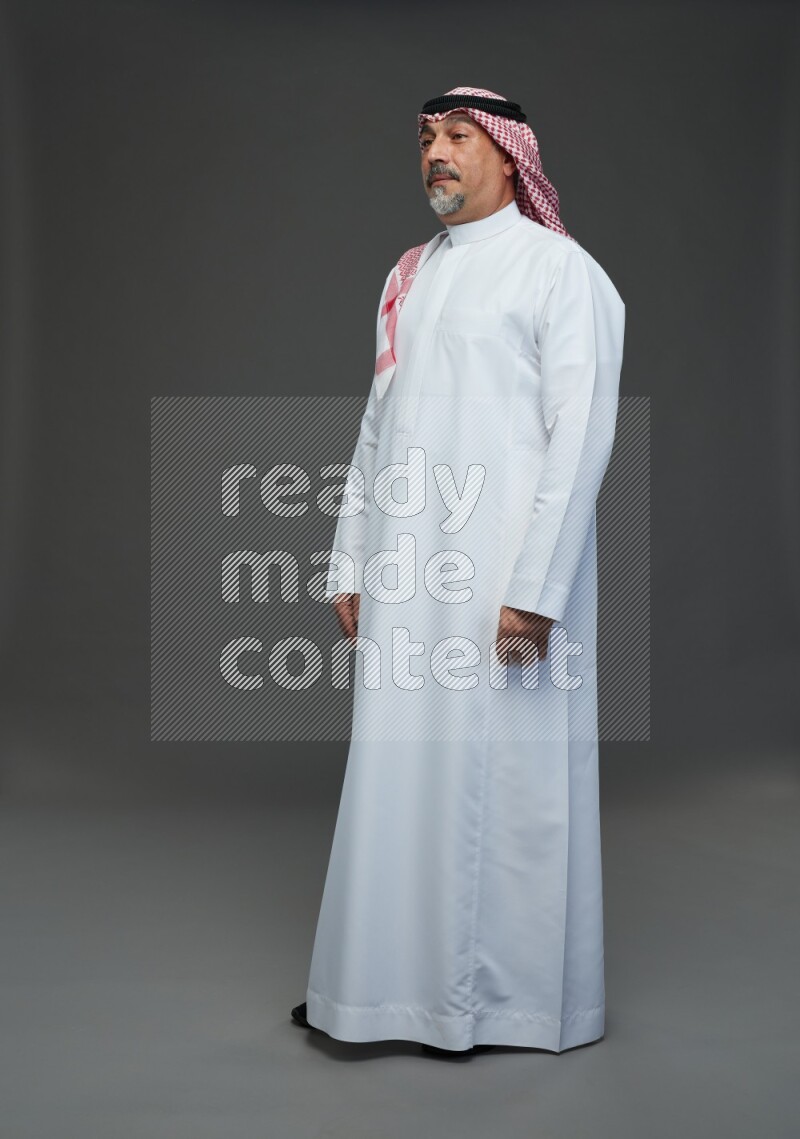 Saudi man with shomag Standing Interacting with the camera on gray background