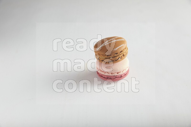 45º Shot of of two assorted Brown Irish Cream, and Pink Litchi Raspberry macarons on white background