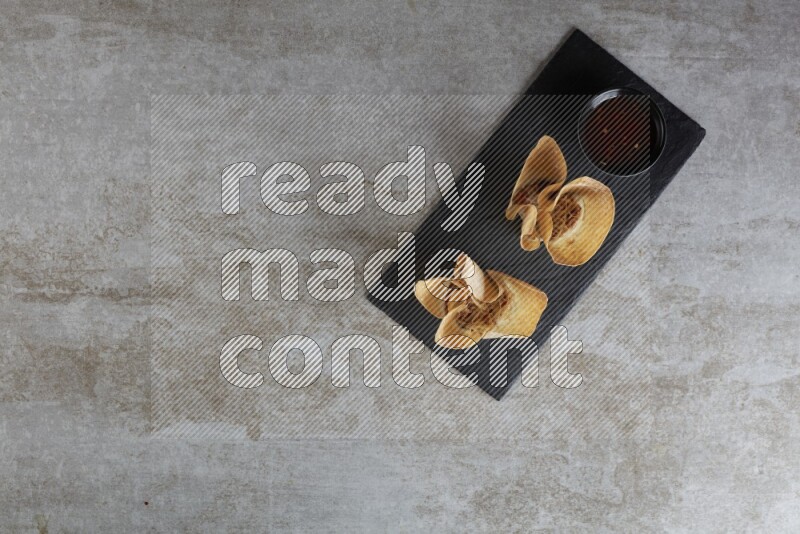 wonton cups with soy sauce ramkin on rectangle slate on grey textured counter top