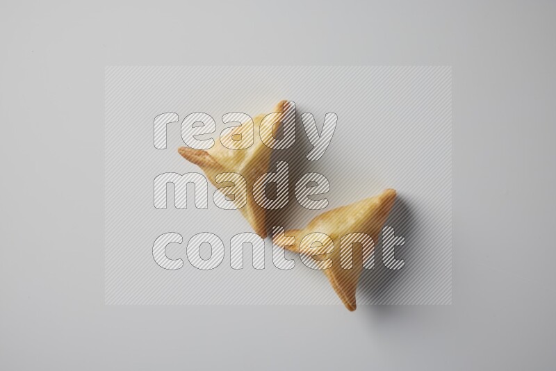 Two fried sambosa from a top angle on a white background