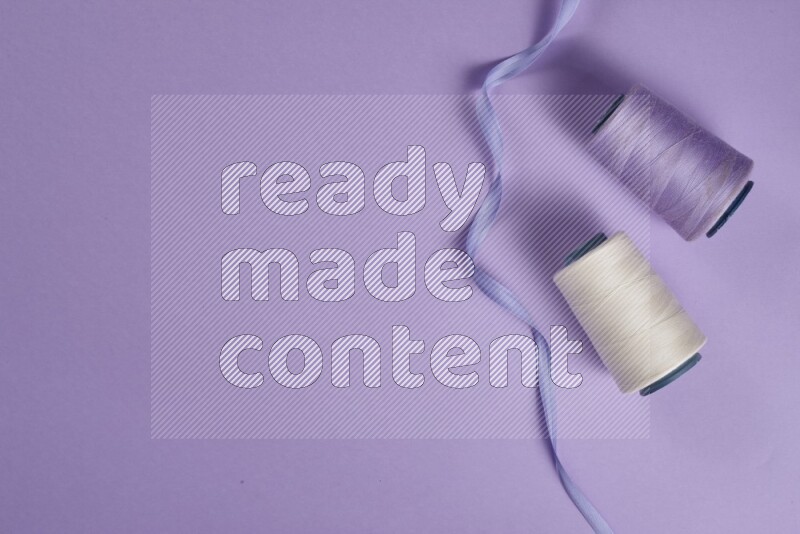 A white and purple collection of sewing and tailoring tools arranged on a purple background