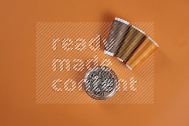 A brown collection of sewing and tailoring tools arranged on a orange background