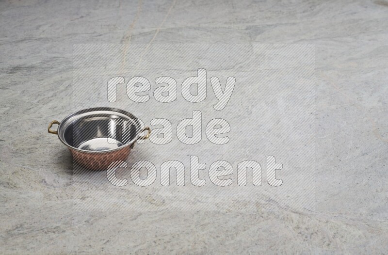 A small copper pot on grey marble background