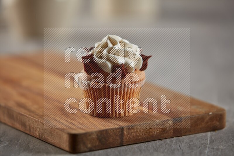 Vanilla cupcake topped with cream on a wooden board