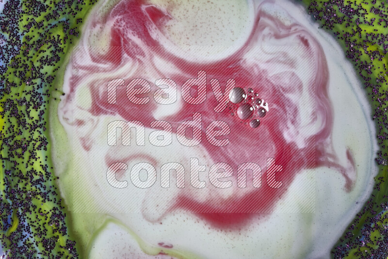 A close-up of swirls of red and white with sparkling purple glitter scattered on green and blue background