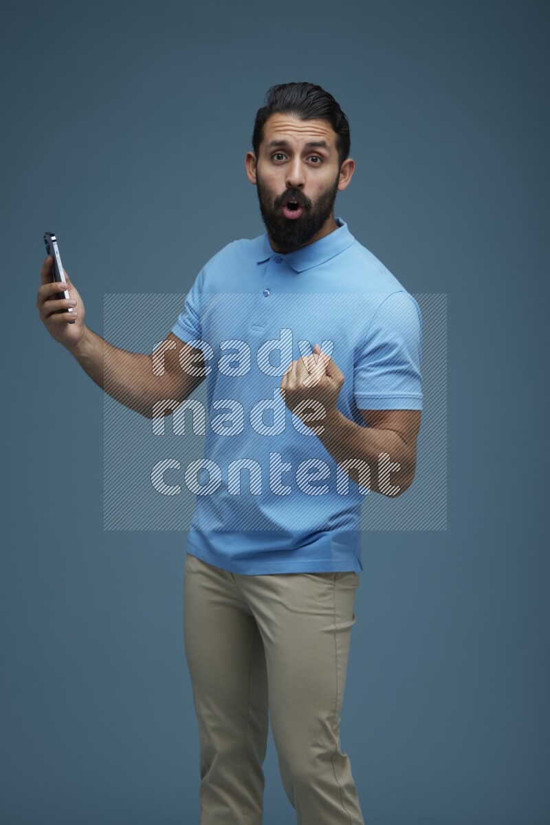 Man posing with a phone in a blue background wearing a Blue shirt