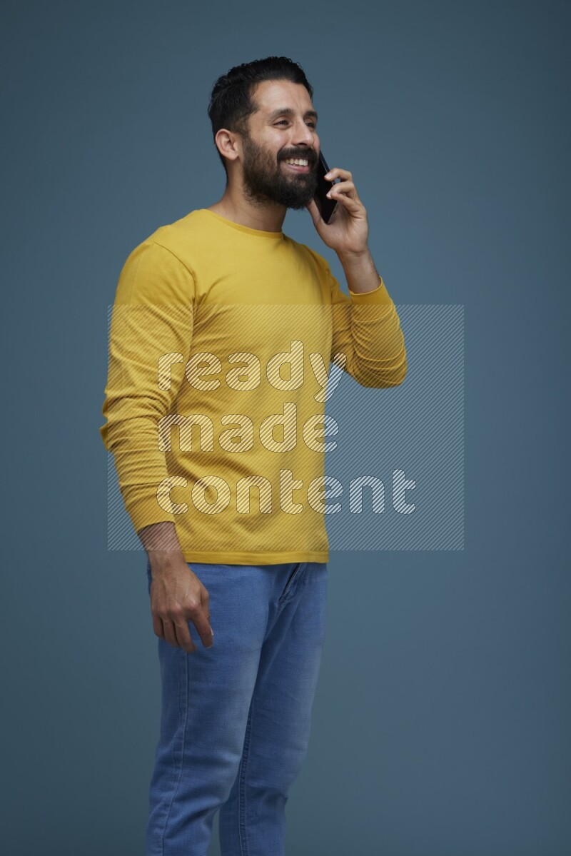 A man having a calling in a blue background wearing a yellow shirt
