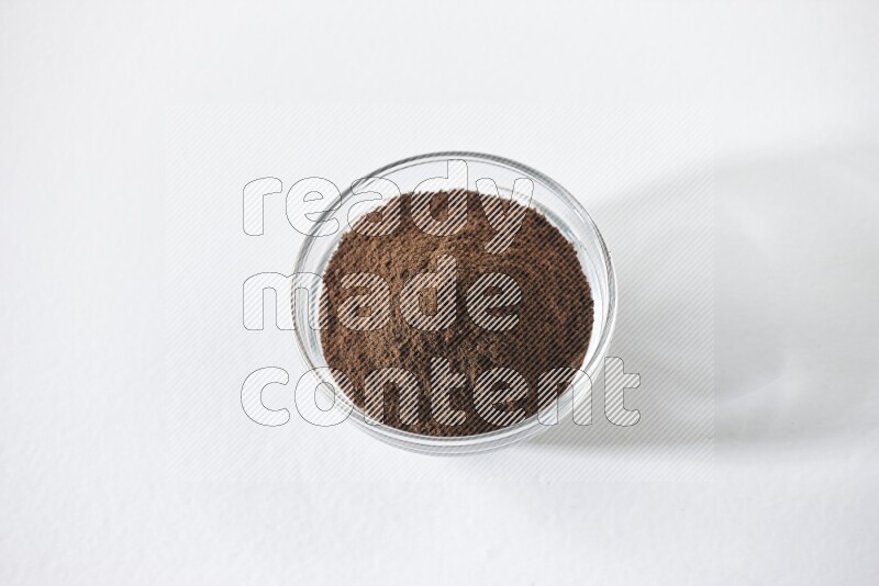 A glass bowl full of cloves powder on white flooring