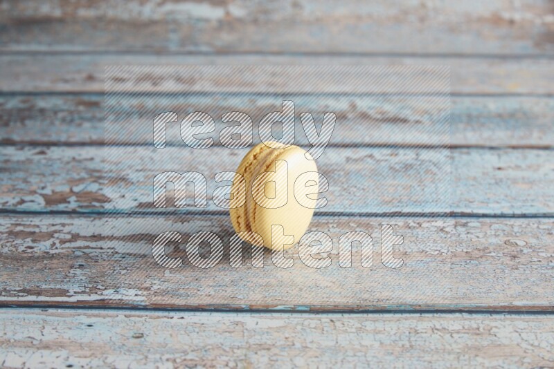 45º Shot of Yellow Vanilla macaron on light blue wooden background