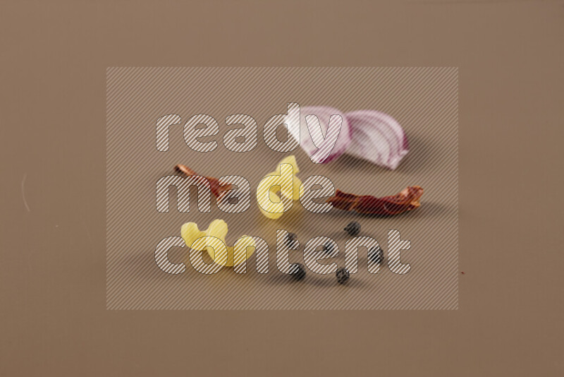 Raw pasta with different ingredients such as cherry tomatoes, garlic, onions, red chilis, black pepper, white pepper, bay laurel leaves, rosemary and cardamom on beige background