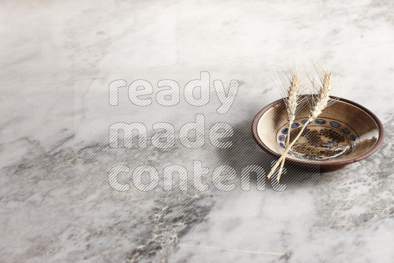 Wheat stalks on decorative pottery plate on grey marble background