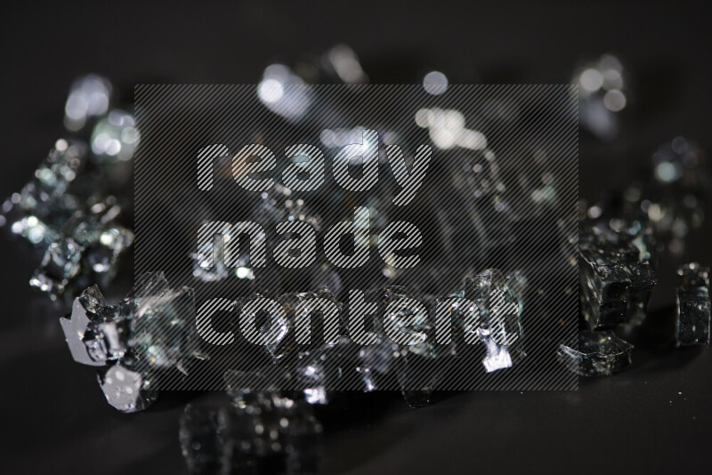 Transparent black fragments of glass scattered on a black background