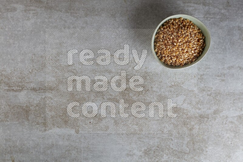 corn kernel in a green ceramic bowl on a grey textured countertop